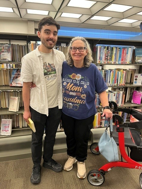 A tall boy and his mother stand in front of bookshelves at the Southport Branch A tall boy and his mother stand in front of bookshelves at the Southport Branch